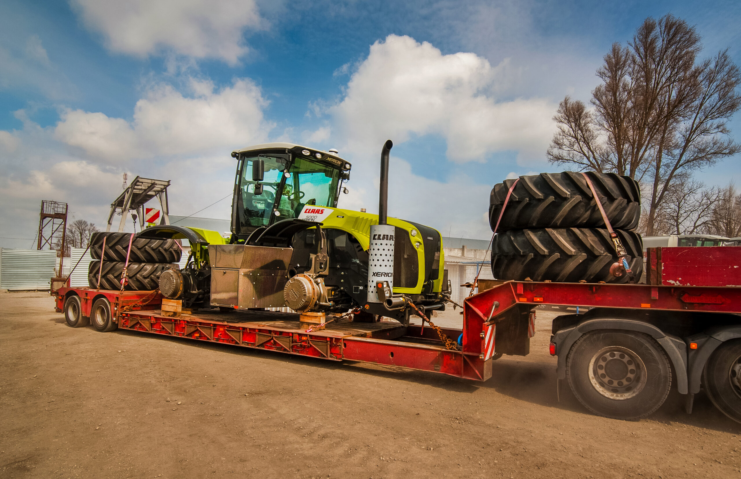 TERNOPIL REGION, UKRAINE – MARCH 29, 2019: A truck on a trailer transports a dismantled tractor to a repair base in preparation for the agricultural work season
